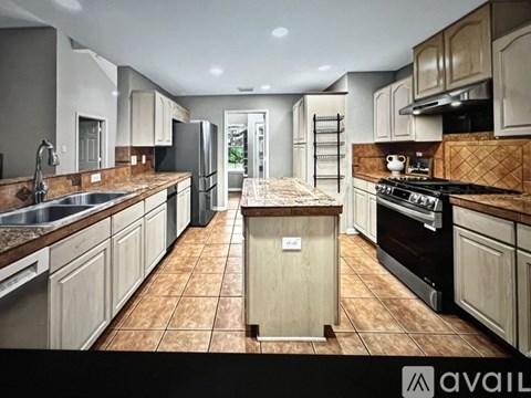 A kitchen with brown tiles and wooden cabinets is available for rent.