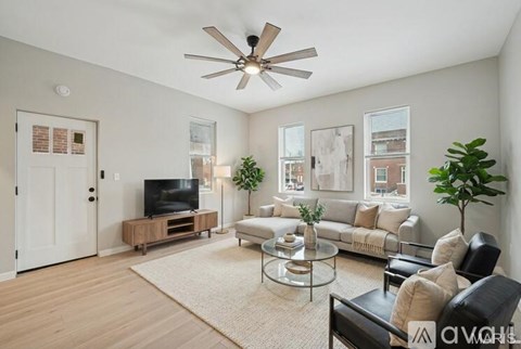 A living room with a television, couch, and a ceiling fan.