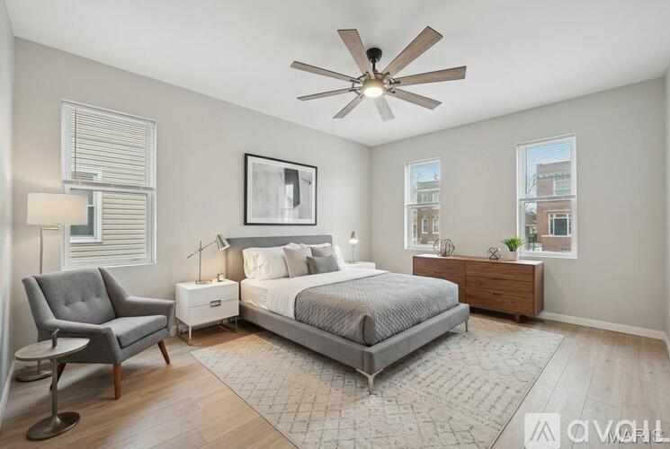 A bedroom with a bed, chair, and a ceiling fan.