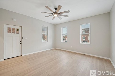 A spacious room with a ceiling fan and hardwood flooring.