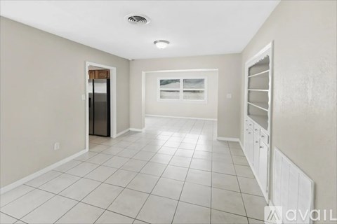 A spacious kitchen with white cabinets and a black refrigerator.