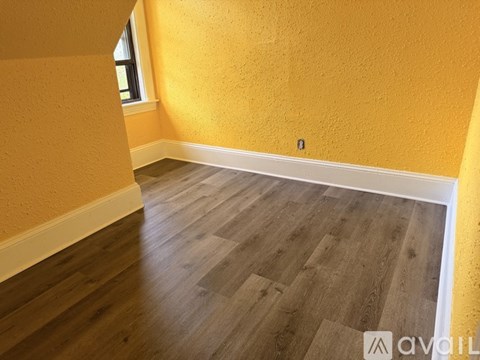 A room with wooden flooring and a window.