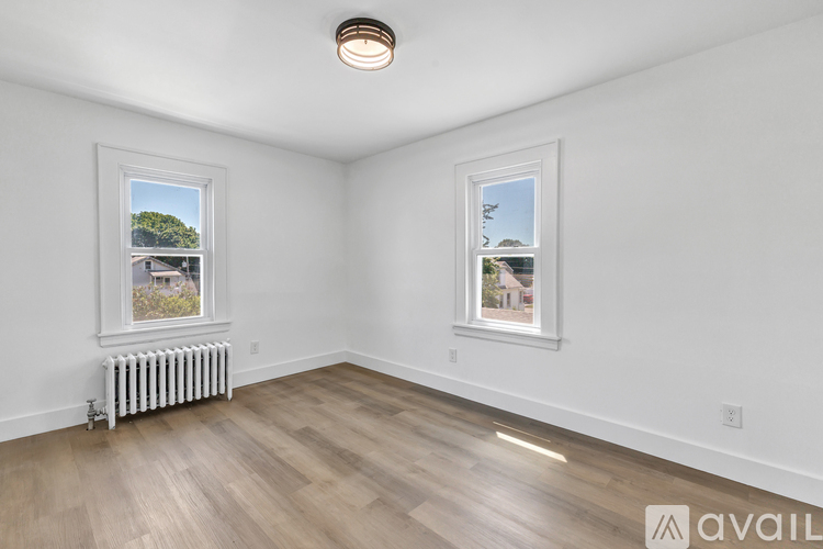 A room with wooden flooring and two windows showing outdoor views.