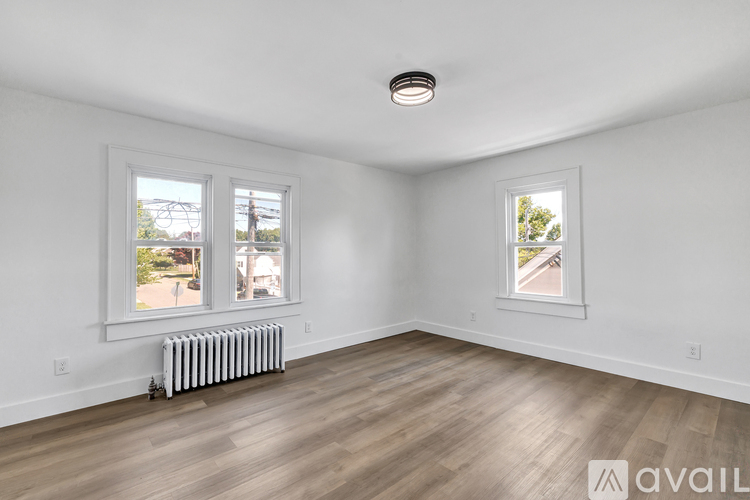 A room with two windows and a white radiator on the floor.