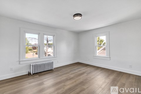 A room with two windows and a white radiator on the floor.