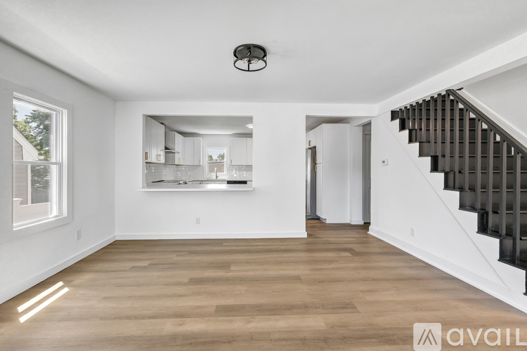 A spacious room with wooden floors and a staircase leading to another room.