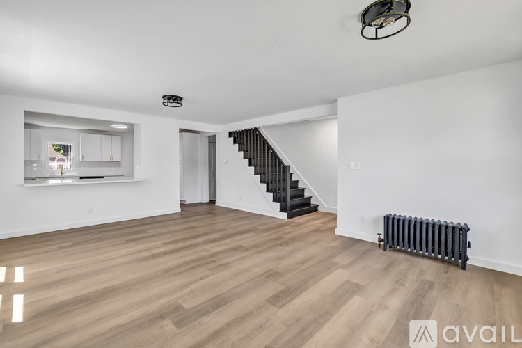 A spacious room with wooden flooring and a staircase leading to another room.