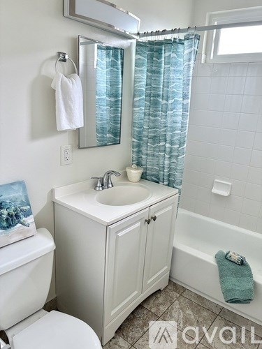 A white bathroom with a toilet, sink, and bathtub.