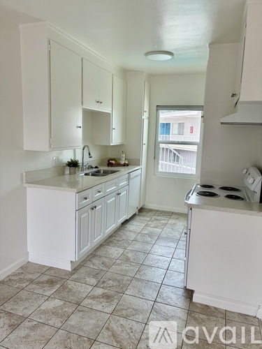 A kitchen with white cabinets and a tiled floor.