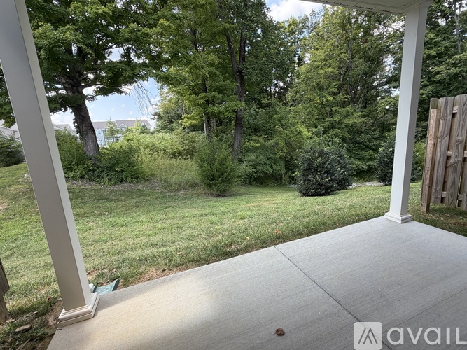 A porch with a view of a green lawn and trees.