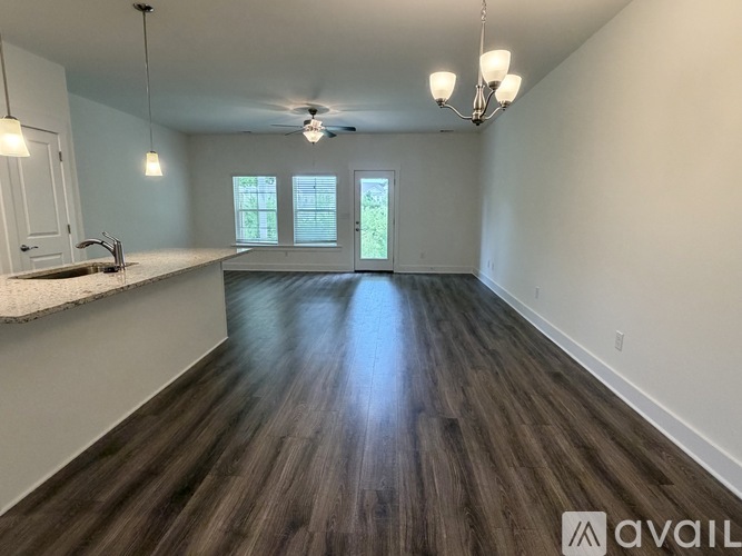A spacious room with wooden flooring and a window overlooking greenery.