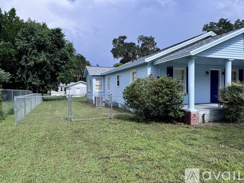 A blue house with a white fence and a green lawn.