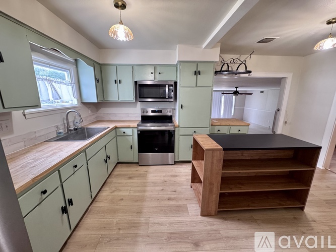 A kitchen with green cabinets and a wooden island.