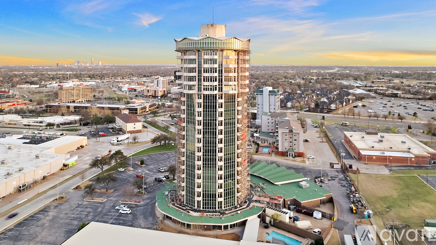 A tall building with a green roof is in the center of a parking lot.