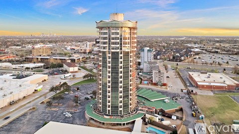 A tall building with a green roof is in the center of a parking lot.