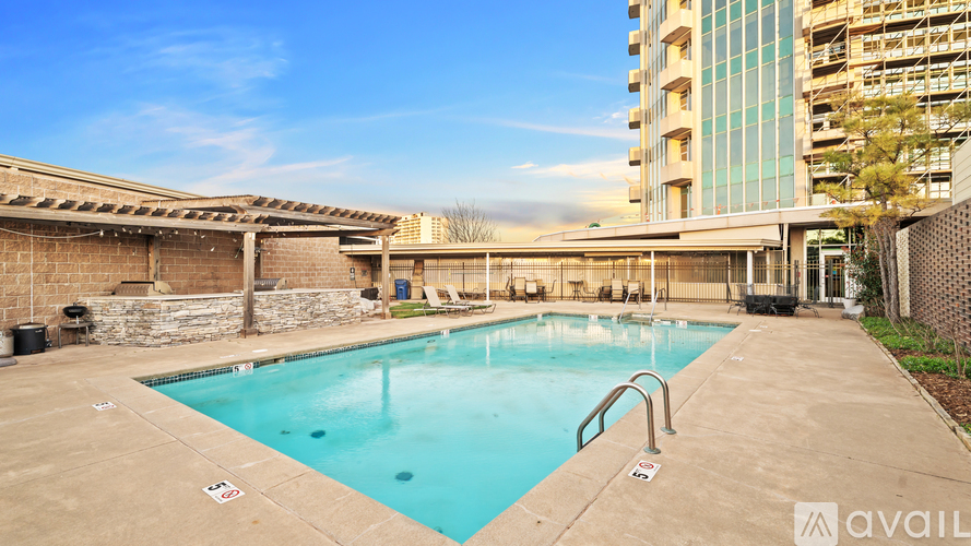 A large outdoor swimming pool with a stone wall and a building in the background.