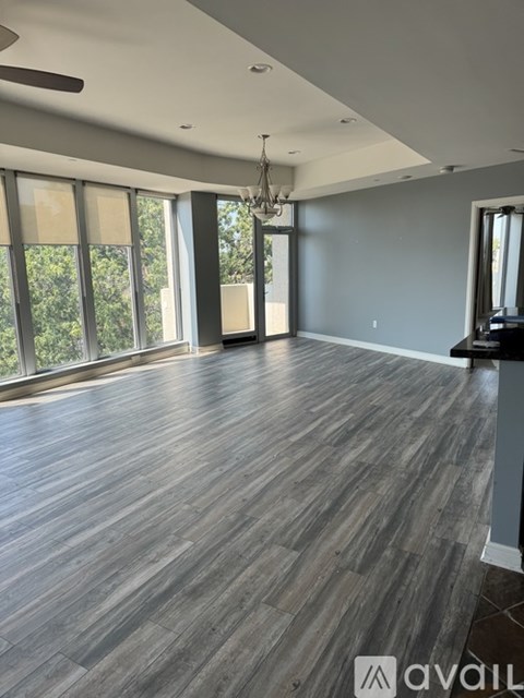 A spacious room with wood flooring and a chandelier.
