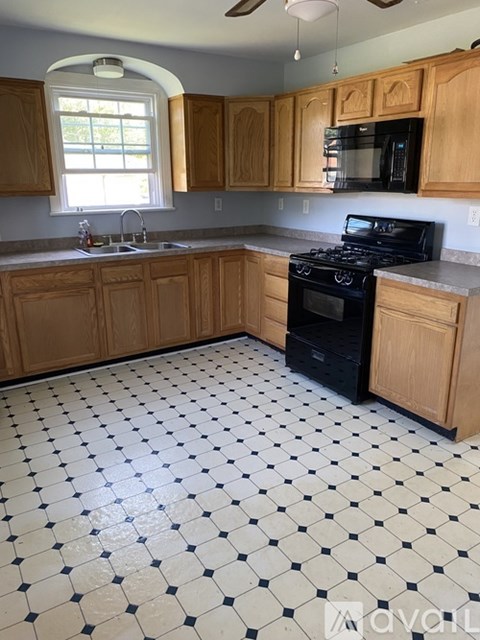 A kitchen with wooden cabinets and a black and white checkered floor.