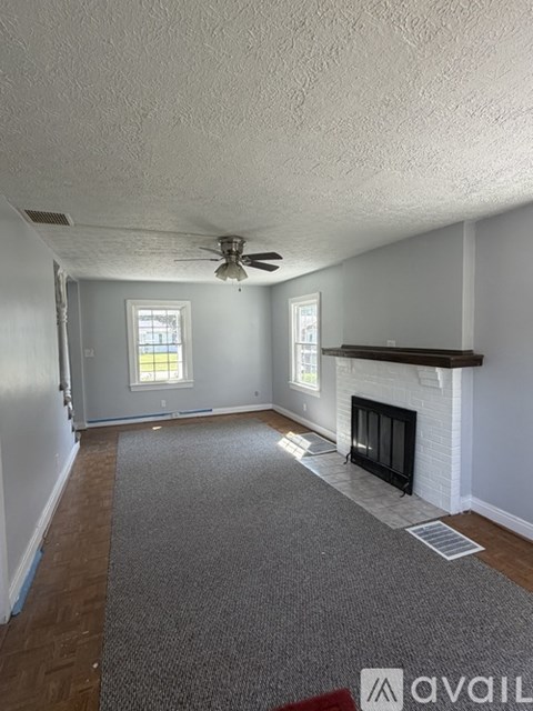A living room with a fireplace and a ceiling fan.
