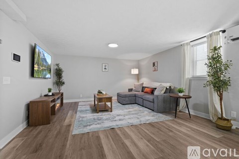 A living room with a grey couch, a wooden table, and a television mounted on the wall.