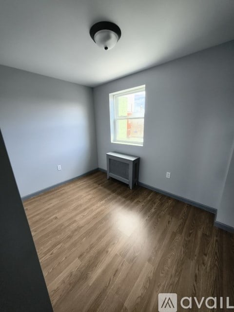 A room with wooden flooring and a window with a view of a building outside.