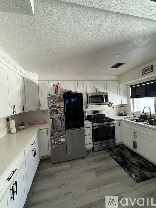 A kitchen with white cabinets and a refrigerator.