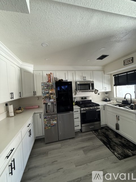 A kitchen with white cabinets and a refrigerator.
