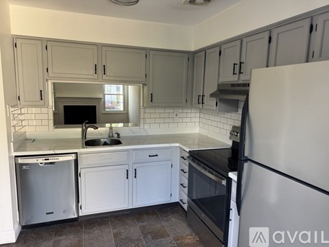 A kitchen with white cabinets and a black fridge.