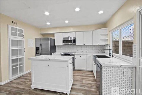 A white kitchen with a refrigerator, sink, and cabinets.