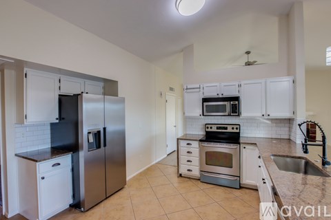 A kitchen with a stainless steel refrigerator and oven, and a white tile backsplash.