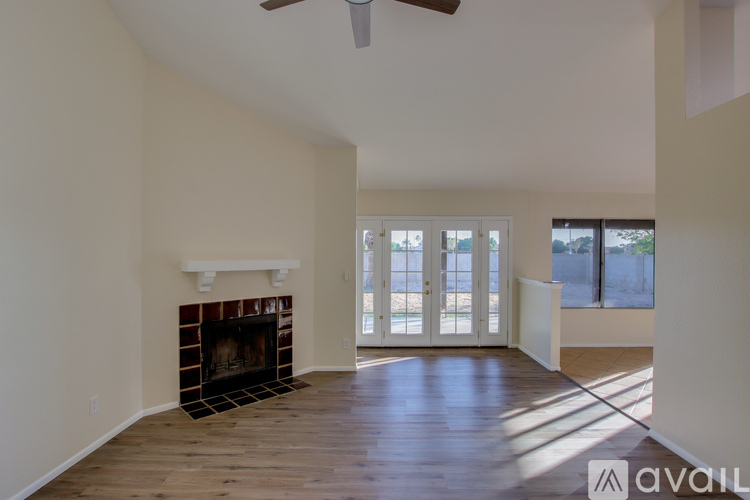 A spacious living room with a fireplace and a ceiling fan.