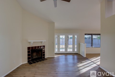 A spacious living room with a fireplace and a ceiling fan.