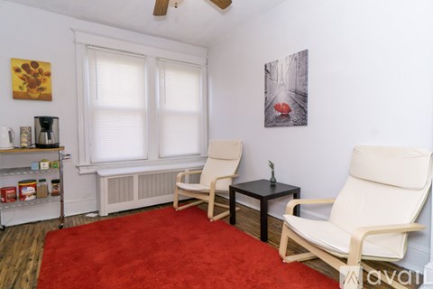 A living room with a red carpet and two white chairs.