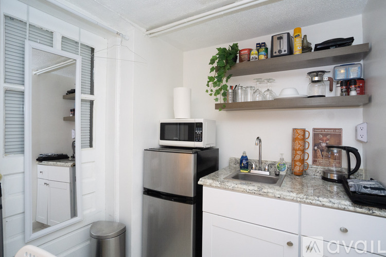 A kitchen with a refrigerator, microwave, and a counter with various items on it.