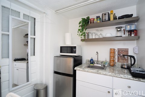 A kitchen with a refrigerator, microwave, and a counter with various items on it.