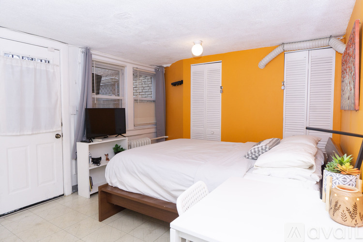 A bedroom with a white bed and a television in the corner.
