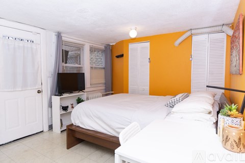 A bedroom with a white bed and a television in the corner.
