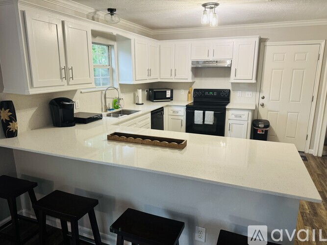 A kitchen with white cabinets and black appliances.
