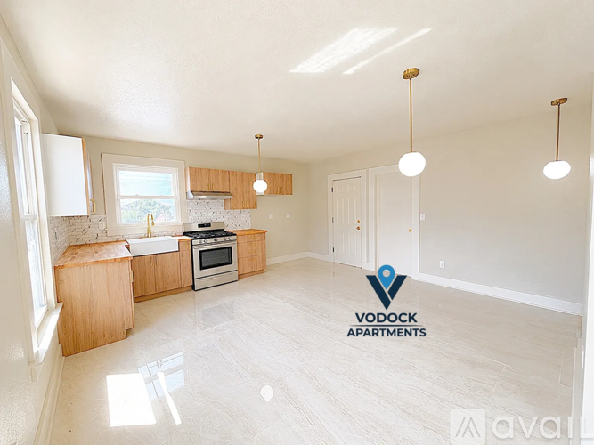 A spacious, well-lit apartment with a kitchen area and a logo for Vodock Apartments.