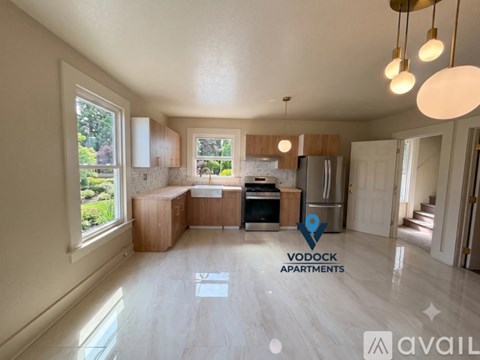 A spacious apartment with a kitchen, dining area, and a view of greenery outside.