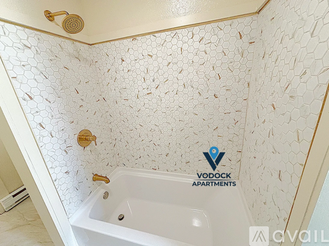 A Vodock Apartments shower with a white tub and gold fixtures.