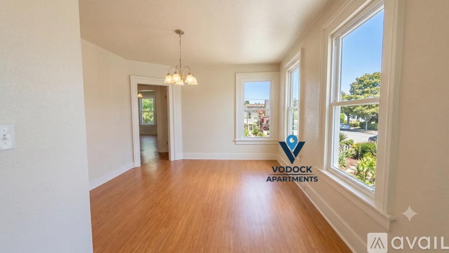 A room with wooden floors and a window showing a view of trees and houses outside.