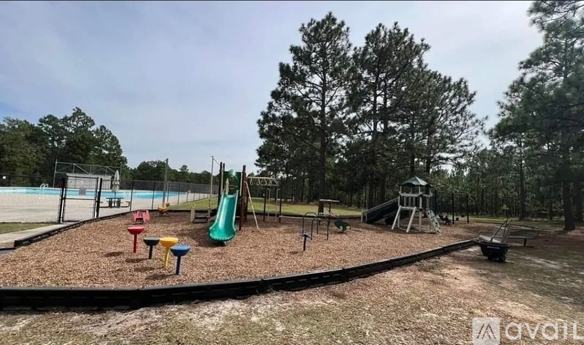 A playground with a green slide and red and yellow toys.