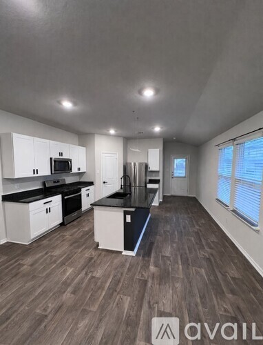 A kitchen with white cabinets and black countertops.