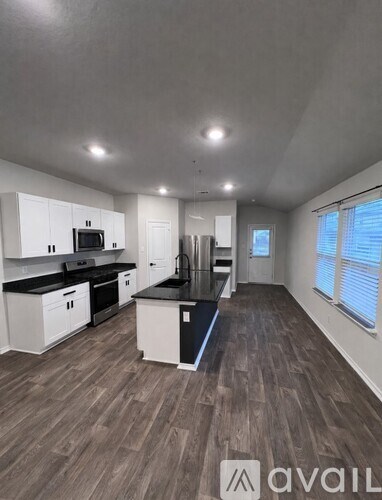 A kitchen with white cabinets and black countertops.