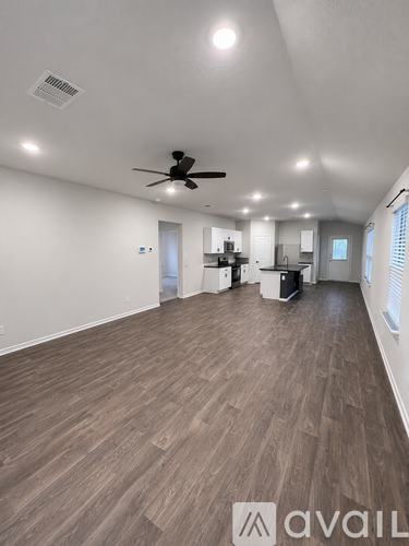 A spacious room with a ceiling fan and wooden flooring.