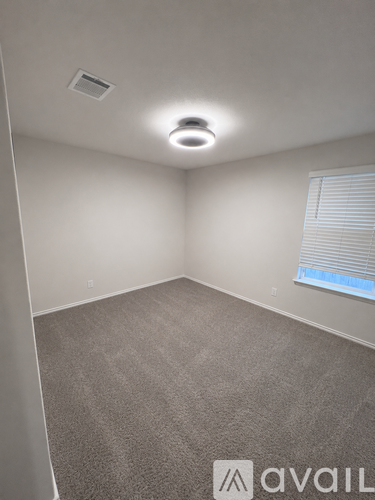 A room with a carpeted floor and a window with blinds.