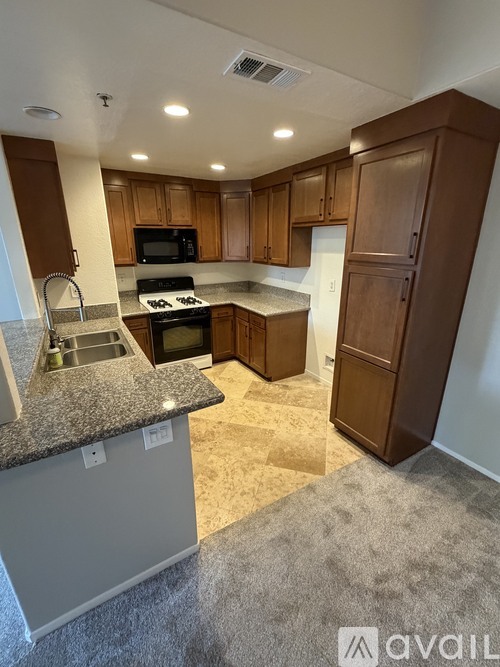 A kitchen with brown cabinets and a granite countertop.