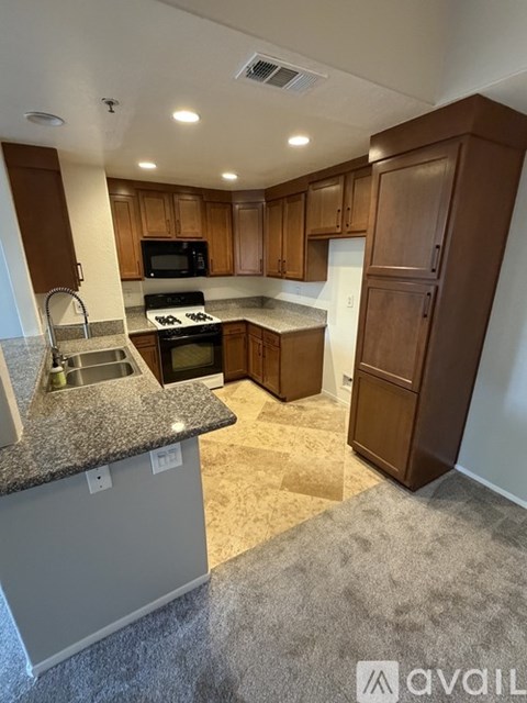 A kitchen with brown cabinets and a granite countertop.