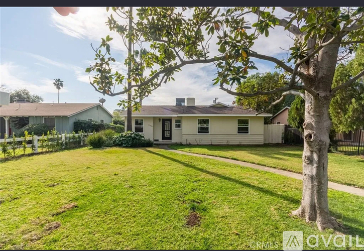 A house with a white fence and a tree in front of it.